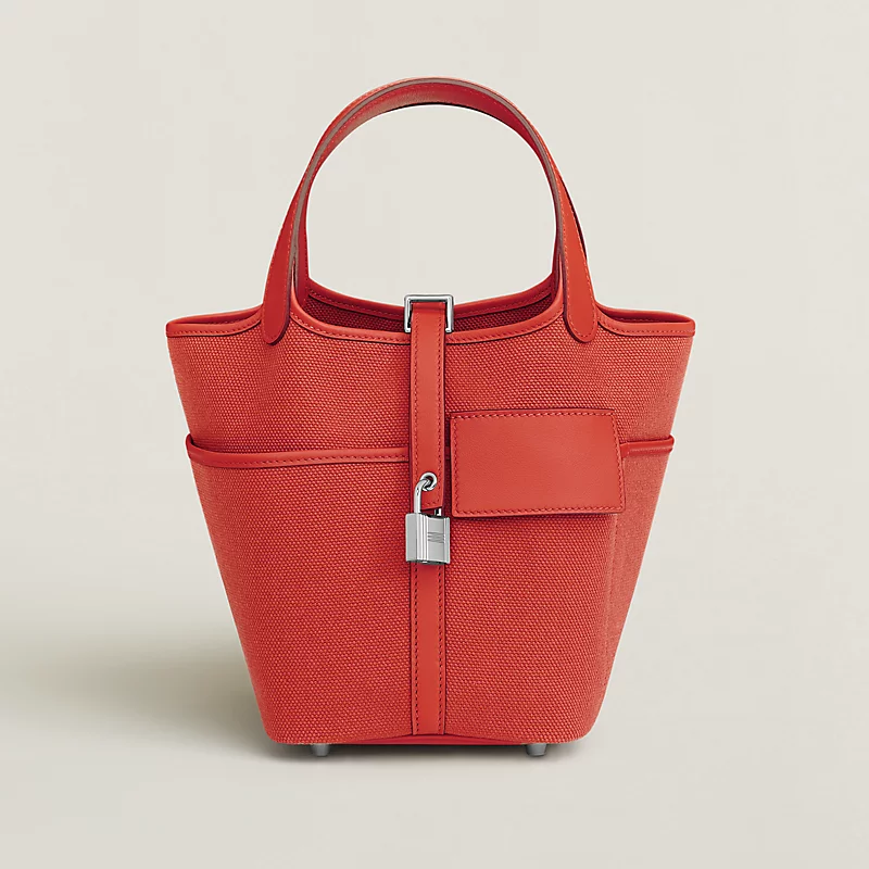 Small red textured tote bag with rounded handles, front pocket, and silver lock detail.
